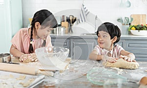 Happy asian family funny kids are preparing the dough, bake cookies in the kitchen