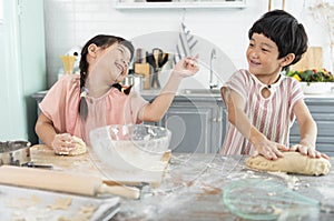 Happy asian family funny kids are preparing the dough, bake cookies in the kitchen