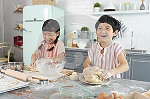Happy asian family funny kids are preparing the dough, bake cookies in the kitchen