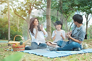 Happy asian family have leisure in public park.Father playing guitar with mother and son clap hands together with enjoying and