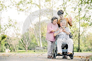 Happy Asian family having fun using smartphone in the park