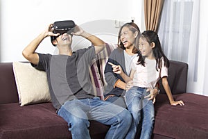 Happy asian family at home wearing virtual reality goggles