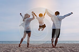 Happy asian family jumping together on the beach in holiday vacation. Silhouette of the family holding hands enjoying the sunset
