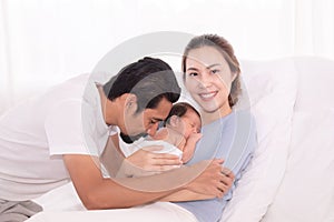 Happy Asian family lifestyle, father hold wife kissing toddler newborn baby with love, mother hug infant in arm sleeping comfort