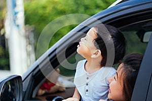 Happy Asian family is looking up in the sky and travelling on the road trip, going for a drive for vacation.