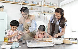 Happy Asian family making preparation dough and bake cookies in kitchen at home. Enjoy family activity together