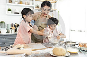 Happy Asian family making preparation dough and bake cookies in kitchen at home. Enjoy family activity together