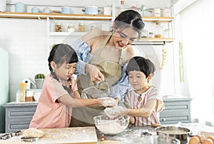 Happy Asian family making preparation dough and bake cookies in kitchen at home. Enjoy family activity together