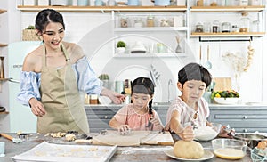 Happy Asian family making preparation dough and bake cookies in kitchen at home. Enjoy family activity together