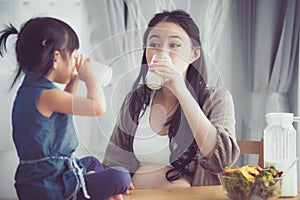 Happy asian family Mom and daughter drink milk.