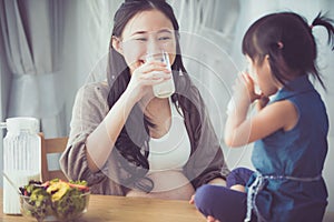 Happy asian family Mom and daughter drink milk.