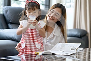 Happy asian family Mom and daughter drink milk at home