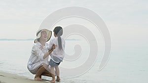 Happy asian family with mother call to daughter hug and peck on the cheek on the beach in vacation for relax