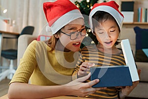 Happy Asian family with mother and daughter open Christmas present gift box together on holiday at home