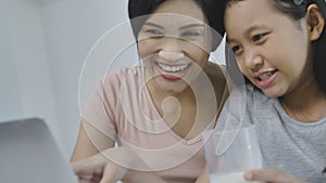 Happy asian family mother and daughter are using laptop at home.