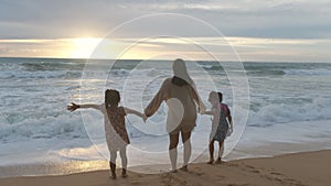 Happy Asian family of mother and daughters having fun playing on the beach during summer vacation at sunset. Summer family trip to