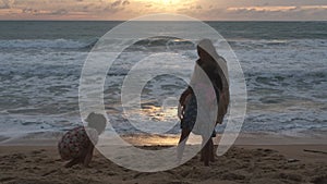 Happy Asian family of mother and daughters having fun playing on the beach during summer vacation at sunset. Summer family trip to