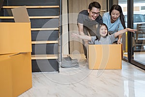 Happy Asian family moving to new house with cardboard boxes.