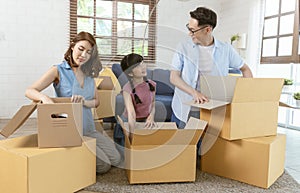 Happy Asian family packing cardboard box during move to new house