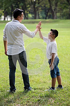 happy asian Family, parents and their children give high five  in park together. father supporting son outside . Support helping