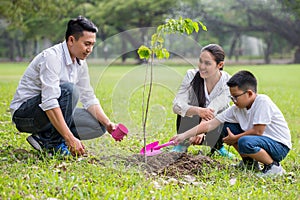 happy asian Family, parents and their children plant sapling tree together in park . father mother and son,boy having fun and