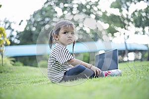 Happy asian family picnic. Daughters playing mobile phones and laptops having fun together while sitting alone on sunny day