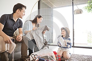 Happy Asian family is preparing for travel at home .Mom daughter and father are packing suitcases for the trip