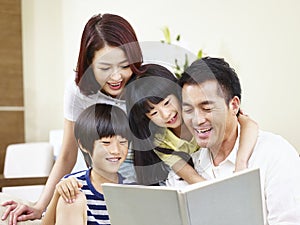 Happy asian family reading a book at home