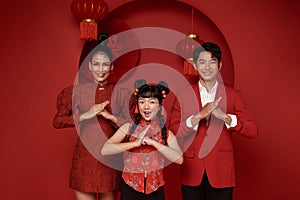 Happy asian family in red casual attire with gesture of congratulation greeting happy chinese new year 2024