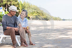 Happy Asian family, senior couple sitting on chairs with backs on beach travel vacation talking together