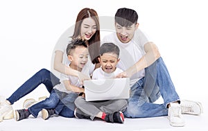 Happy Asian family sitting on white floor and using the laptop