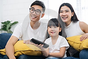 Happy Asian family spending time by watching tv together on sofa in living room. family and home concept.