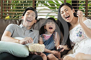 Happy Asian family spending time by watching tv together on sofa in living room. family and home concept.