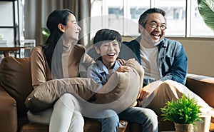 Happy Asian family spending time by watching tv together on sofa in living room. family and home concept.