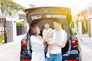 Happy Asian family standing on the back of SUV car with smile and happiness.