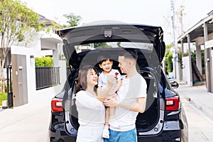 Happy Asian family standing on the back of SUV car with smile and happiness.