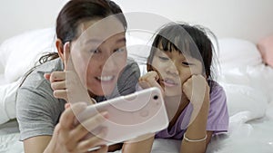 Happy Asian family taking selfie with smartphone at bedroom.