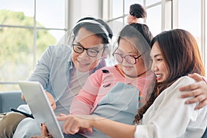 Happy asian family with their daughter down syndrome child sitting on sofa  have fun using laptop watch a movie for education ,