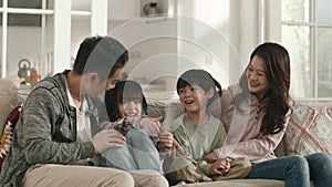 happy asian family with two children watching tv together at home