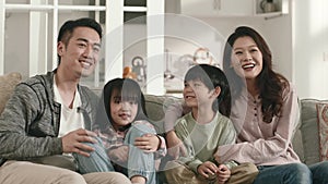 happy asian family watching tv together at home
