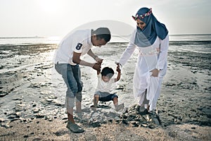 Happy asian family wearing casual and playing with mud at the muddy beach