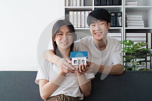 Happy asian family young couple holding house bank to save for saving money wealth to buy real estate for new home