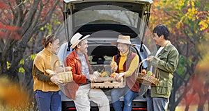Happy Asian farmer family with senior parent are carrying produce harvest with homegrown organics apple, squash and pumpkin with