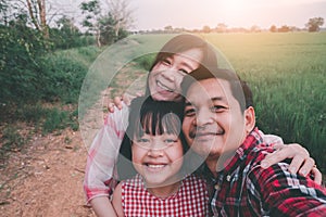 Happy asian farmers family take selfie photo with hugging and smiling at rice field.Agriculture or culture concept