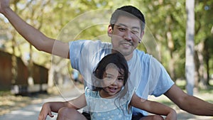 Happy Asian father and daughter sitting with outstretched arms