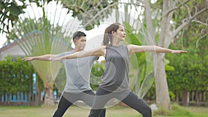 Happy asian father doing training exercises to mother on yoga mat in grass park at the day time