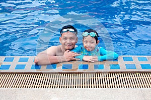 Happy asian father hugging his daughter  in swimming pool