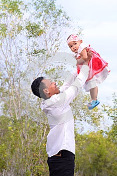 Happy Asian father picks up and throws his lifting a cute child on nature. Father`s day