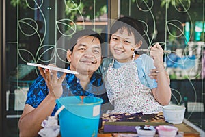 Happy asian Father `s day.Funny smiling father and her daughter painting and drawing with watercolor