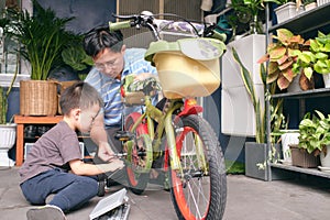 Happy Asian Father and son spend time together, Dad and son playing and repairing bicycle wheel at home